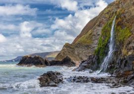 Lais Puzzle - Ein Wasserfall an der walisischen Küste in dem kleinen Fischerdorf Tresaith. Das Meer ist wild, ebenso wie der weiß-blaue Wolkenhimmel. Im Hintergrund die hohen Klippen - 500 & 1.000 Teile