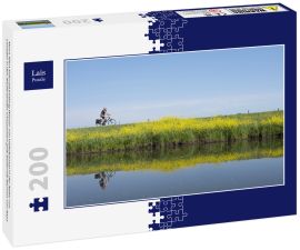 Lais Puzzle - Mann fährt Fahrrad entlang Wasser von Valleikanaal in der Nähe von Leusden in den Niederlanden und passiert gelb blühende Blumen von Raps - 200 Teile
