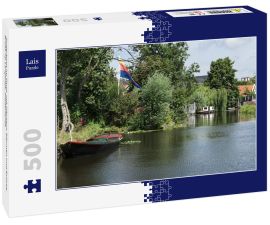 Lais Puzzle - Ruderboot im Fluss, mit Häusern, Bäumen und Brücke. Broek op Langedijk, Niederlande - 500 Teile