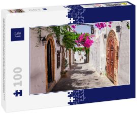Lais Puzzle - Enge Straße in der Stadt Lindos auf der Insel Rhodos, Dodekanes, Griechenland. Schöne malerische alte weiße Häuser mit Blumen. Berühmtes Touristenziel in Südeuropa - 100 Teile