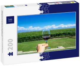 Lais Puzzle - Männliche Hand hält ein Glas Wein mit Anden und Weingut im Hintergrund in Mendonza, Argentinien - 200 Teile